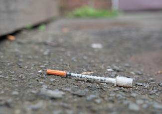 Drug Complaints: a needle left outside on some asphalt.