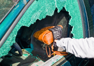 Vol dans un véhicule: un voleur s'emparant d'un sac à main dans un véhicule par une vitre fracassée.