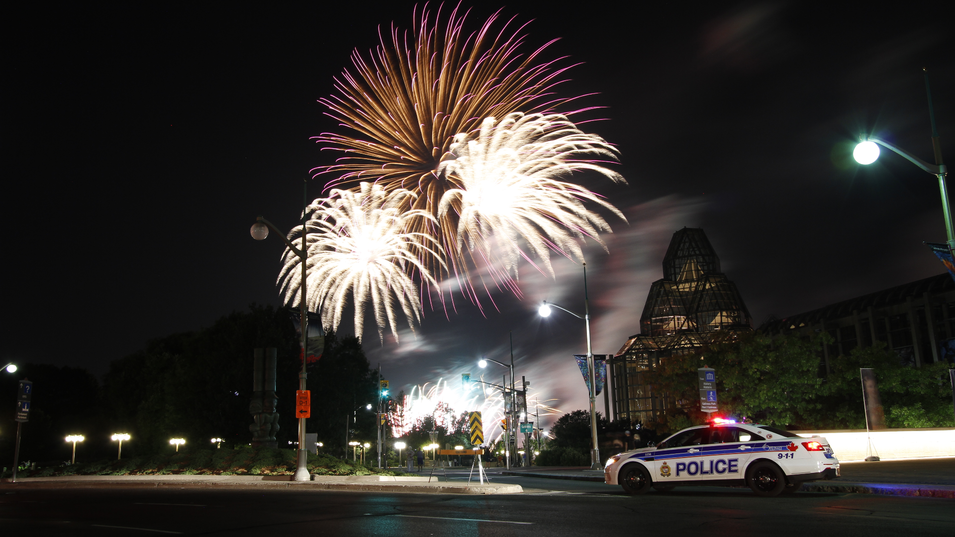 Police cruiser parked in front of a Canada Day fireworks display