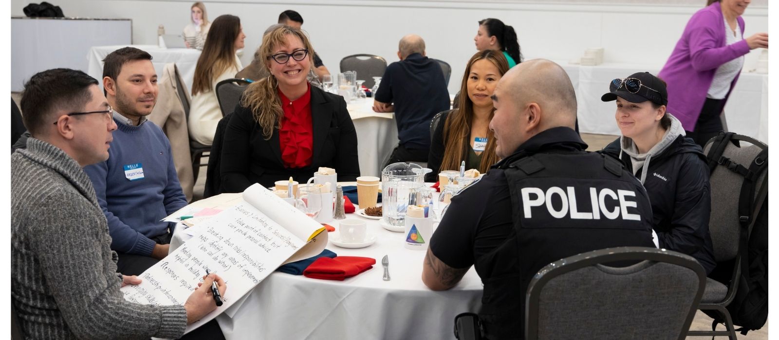 Police officer sitting around a table with community members 
