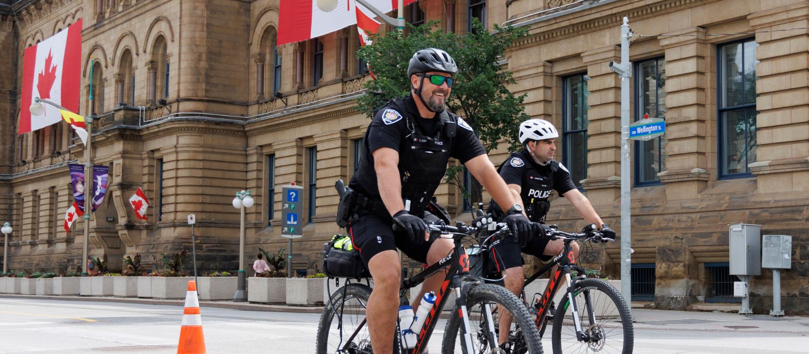 Deux agents de police d'Ottawa à vélo devant un immeuble du centre-ville d'Ottawa.