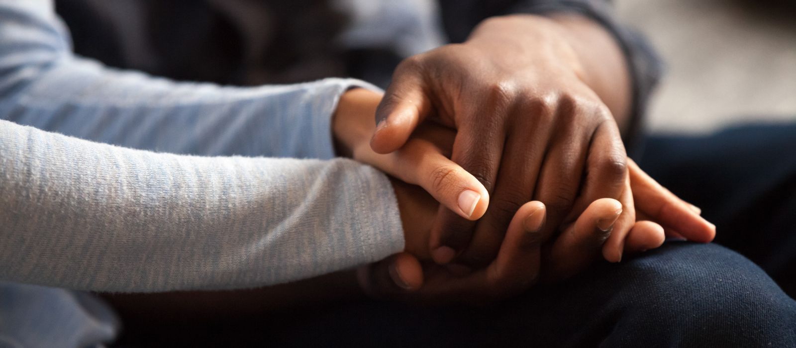 Clasped hands resting in someone's lap.