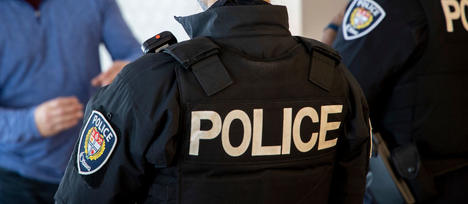 Two police officers with their backs to the camera speaking with a member of the public.