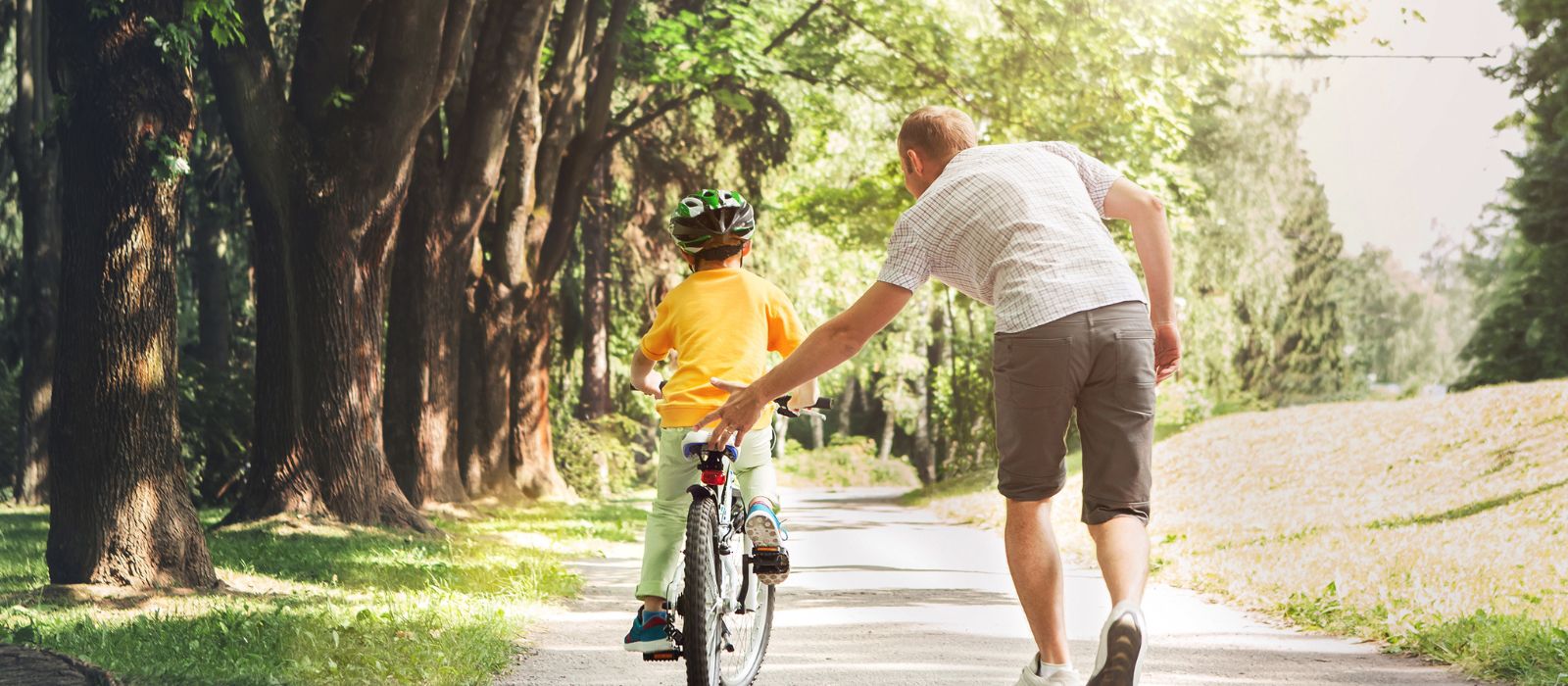 Un homme apprend à un enfant à faire du vélo dans un parc.