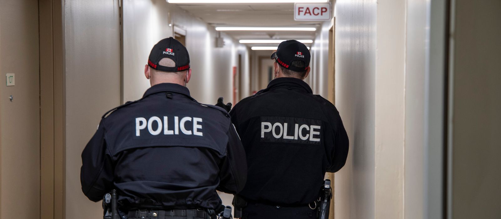 Deux agents de police d'Ottawa marchant dans le couloir d'un immeuble d'habitation.