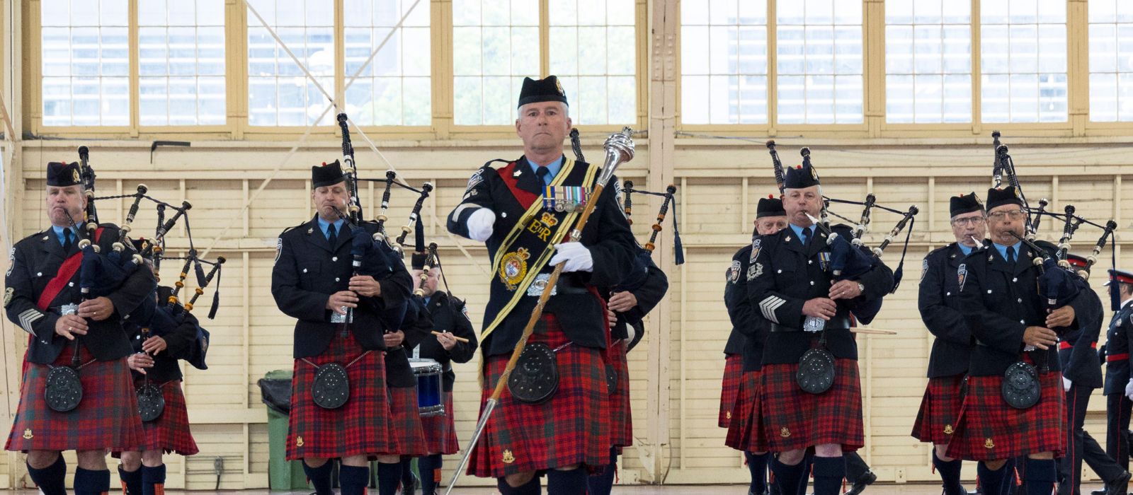 Ottawa Police Pipe Band marching and playing their instruments at an indoor event.