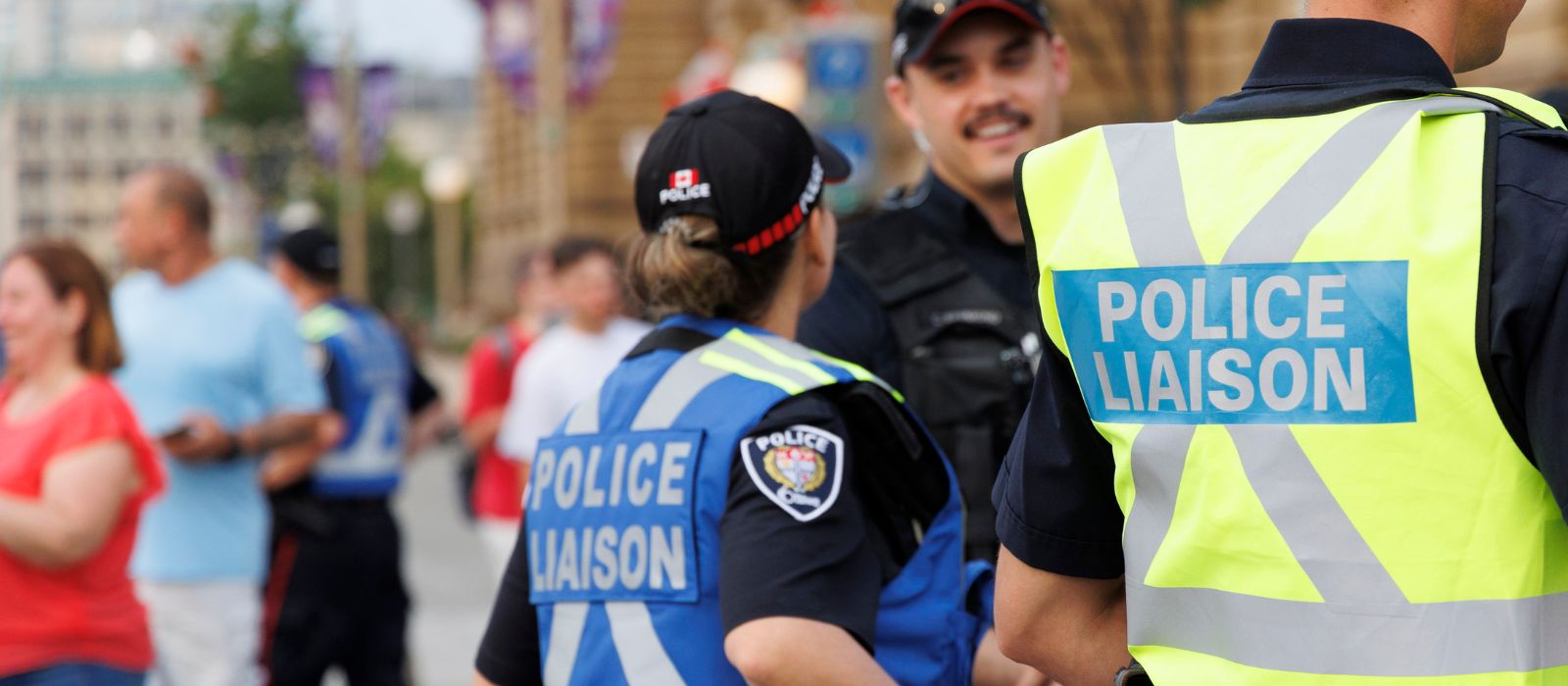 Police Liaison Officers stand in a crowd conversing.