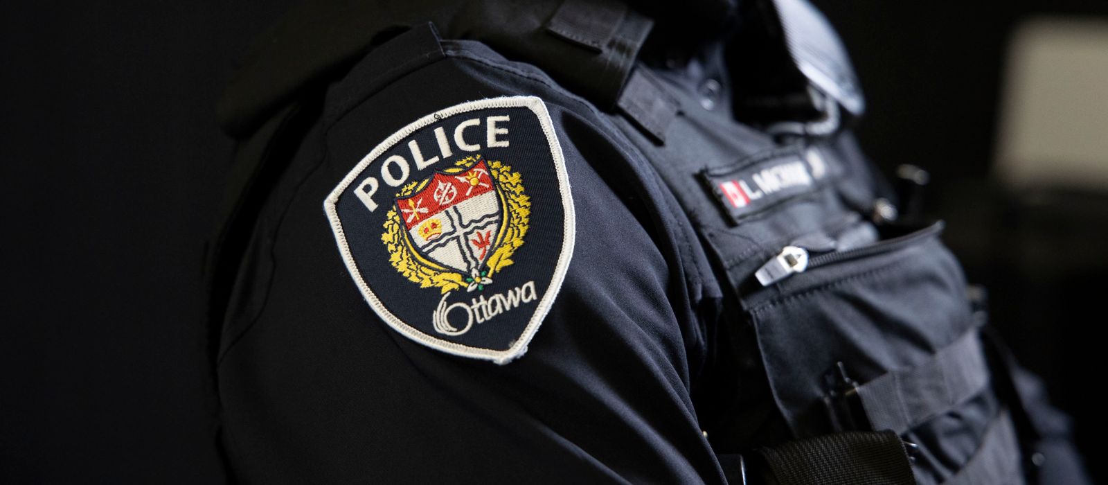Member of the Ottawa Police Service standing in profile. The OPS logo is visible on their shoulder.