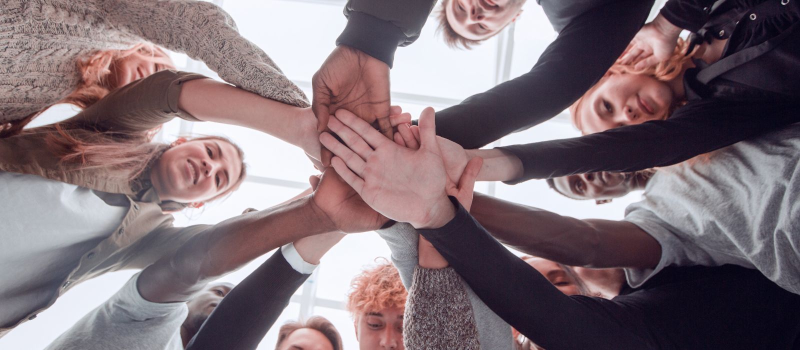 A group of youth standing in a circle with hands piled into the centre.