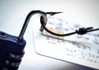 Fraud-unauthorized use of payment method: a lock and a fishing hook placed over a credit card.