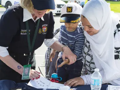 Photo of volunteer helping a mother and child with the child print program.