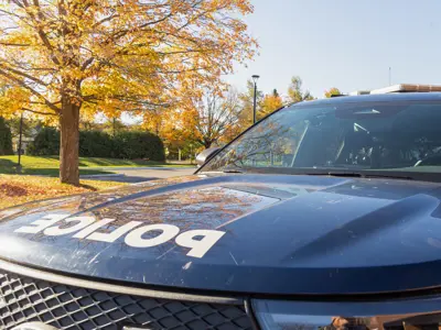 Ottawa Police cruiser outside with fall foliage. / Une voiture de police d'Ottawa garée dehors, avec les couleurs de l'automne en arrière-plan.