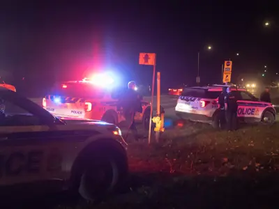 Three Ottawa Police vehicles pulled to the side of the road at night. / Trois véhicules de la police d'Ottawa étaient garés sur le bord de la route, de nuit. 