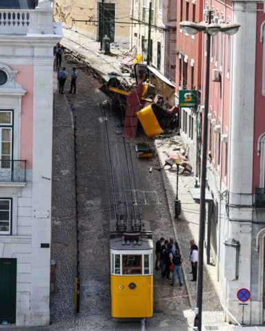Crash site in Lisbon, showing the Gloria funiculars, one jammed at the bottom of the hill and the other crashed into pieces against a building down a narrow hill.