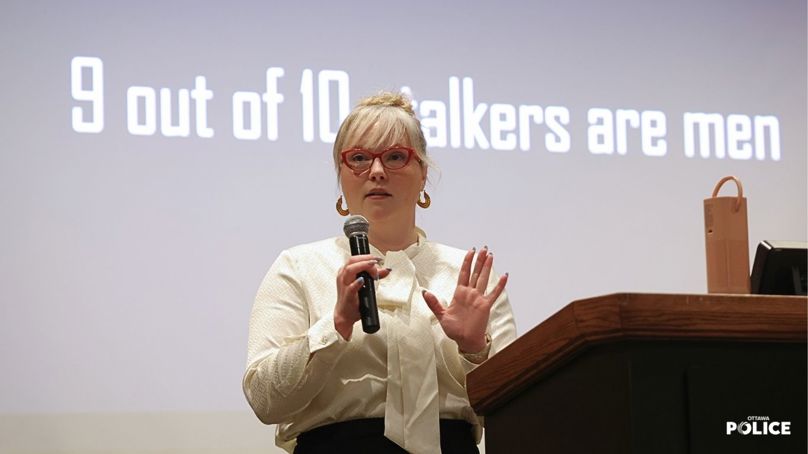Julie Lalonde durning her keynote in front of a screen that reads "9 out of 10 stalkers are men."