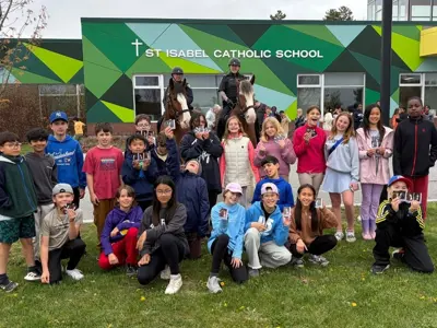 Students with two mounted unit horses in front of school