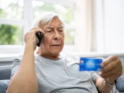 Elderly man holding a credit card while talking on the phone / Un homme âgé tenant une carte de crédit tout en parlant au téléphone