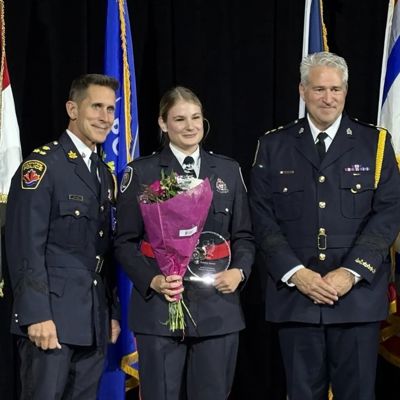 Cst. Victoria Hanniman and two senior officers by her side, she holds a bouquet of flowers and a glass award, as she poses for a picture after receiving the OWLE award for bravery at the OWLE gala in Brampton on May 1st.